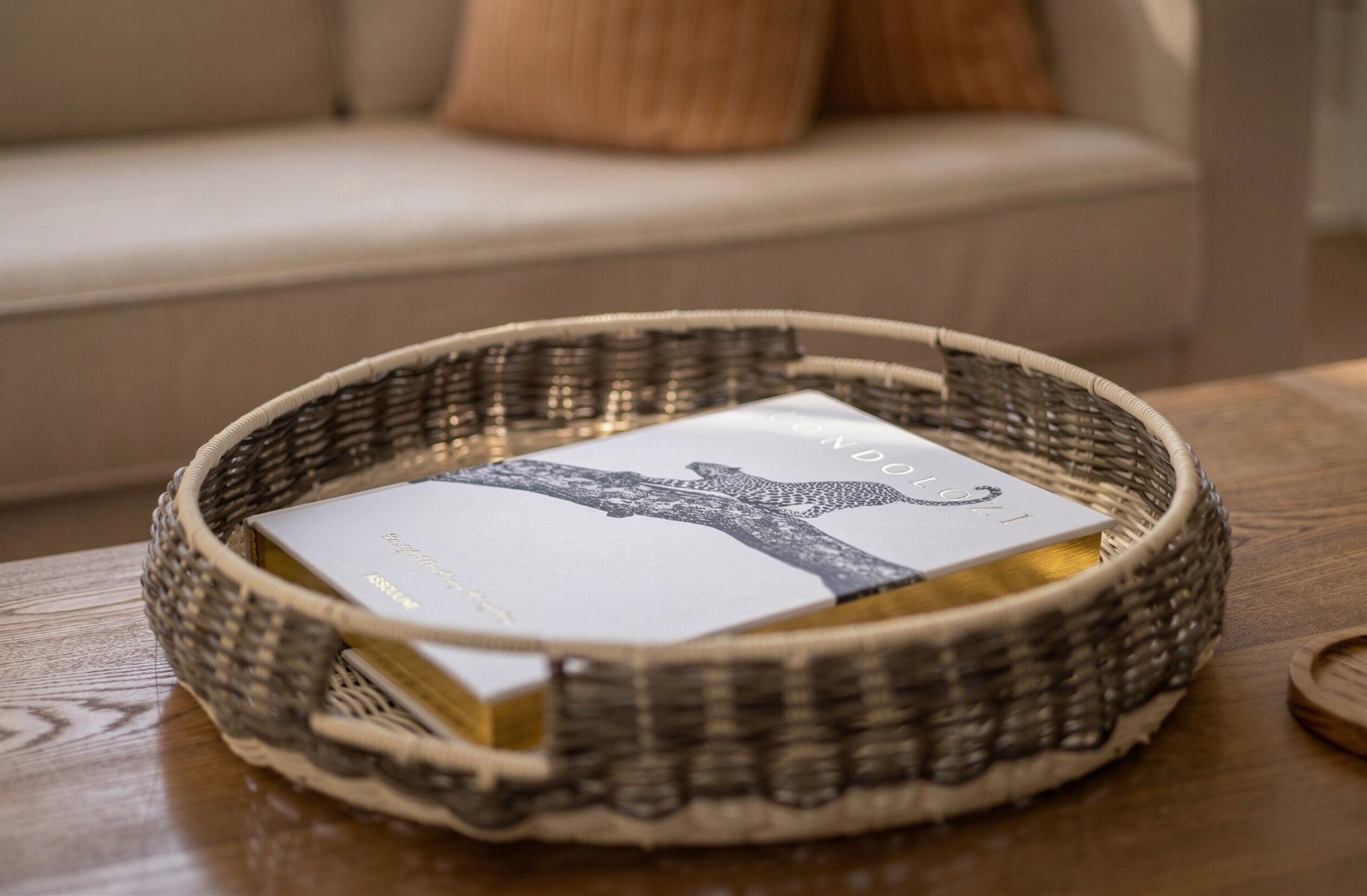 Livre dans un plateau tressé sur une table en bois.
