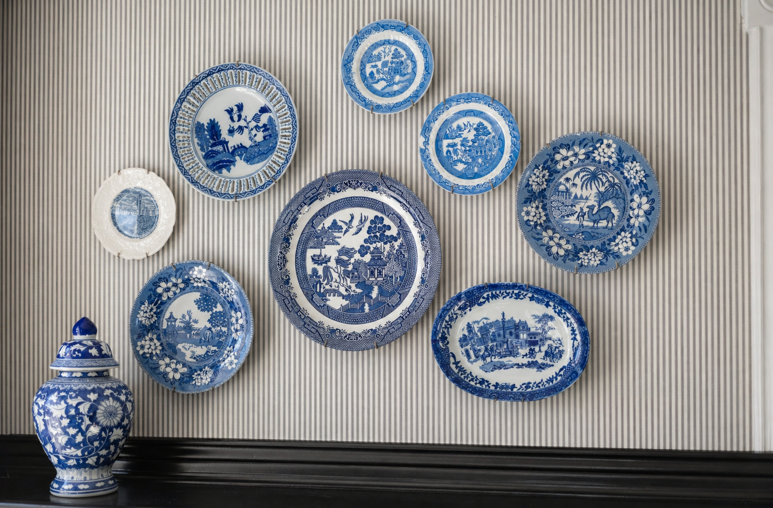 Collection d’assiettes décoratives bleues et blanches disposées au mur dans une chambre.