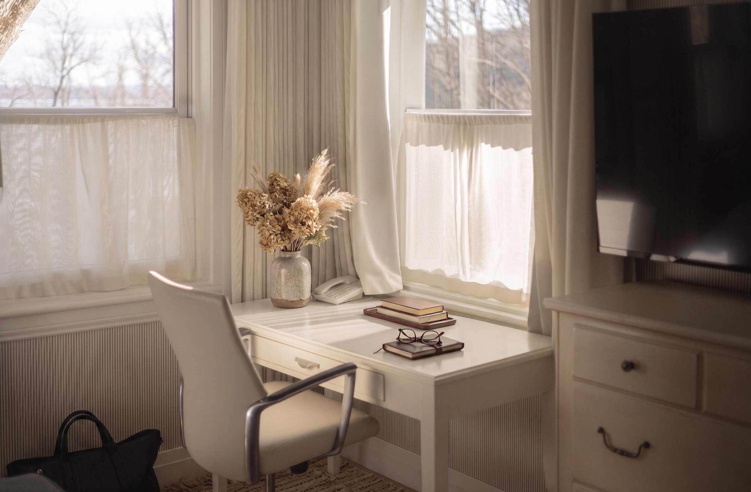 Coin bureau lumineux avec chaise élégante, livres et lumière naturelle près de la fenêtre.