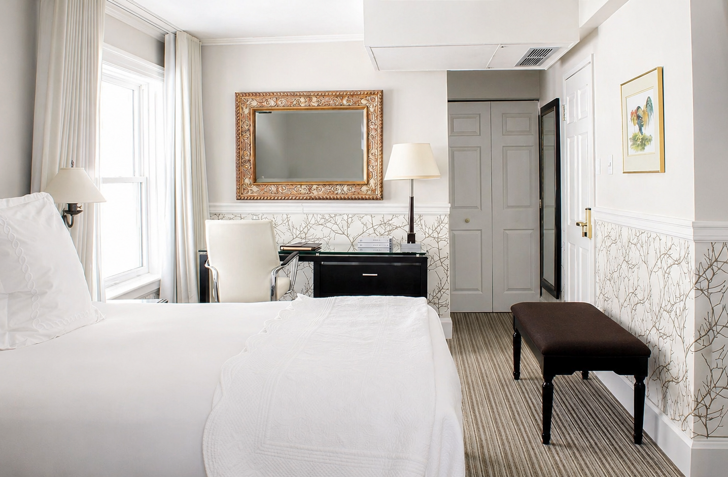 Chambre avec lit blanc, espace bureau et lumière naturelle.