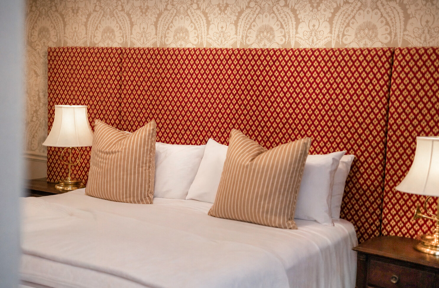 Lit confortable avec tête de lit capitonnée à motif rouge et coussins décoratifs.