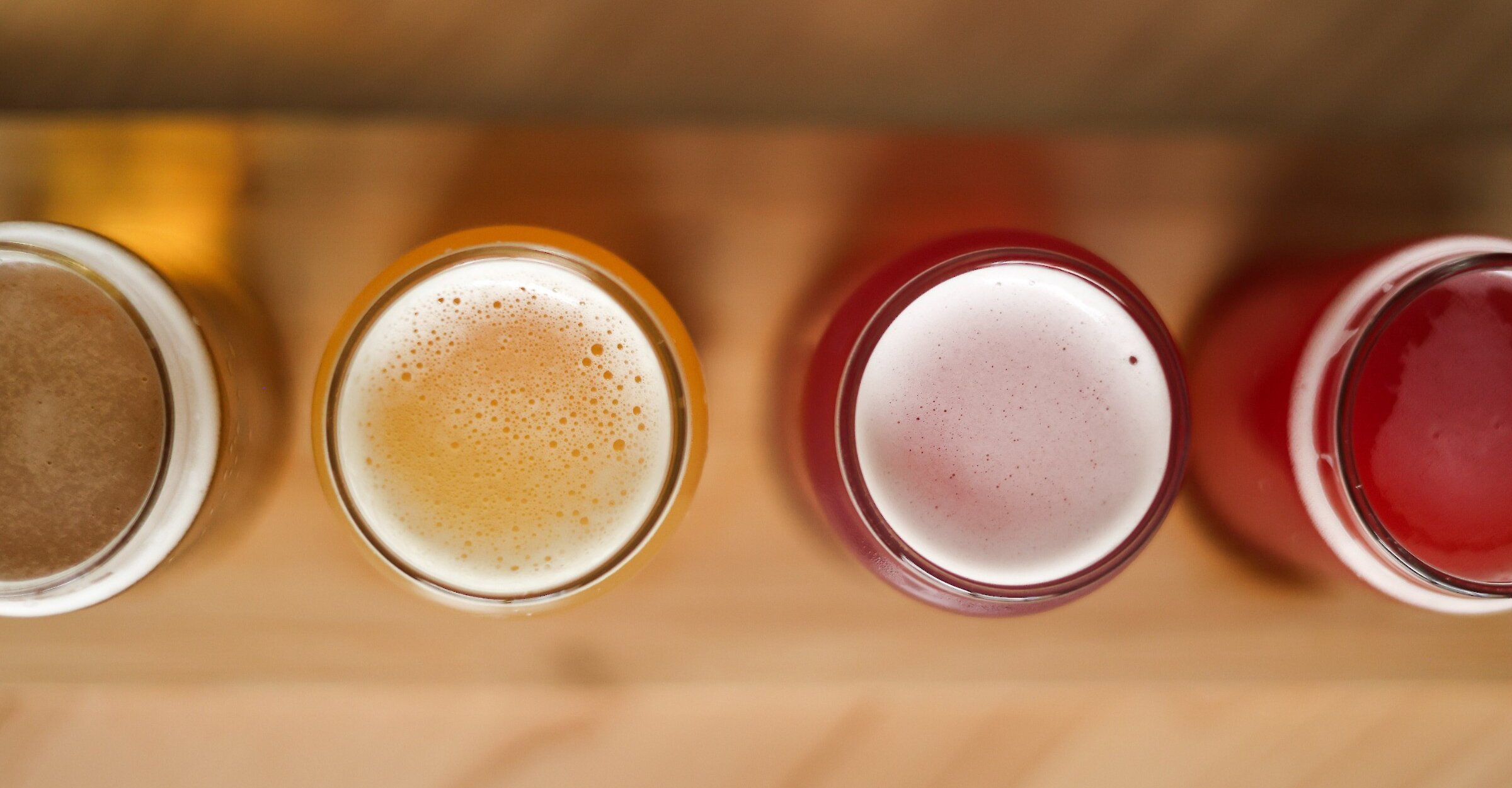A selection of freshly crafted beverages viewed from above, showcasing a variety of vibrant colors and frothy textures.