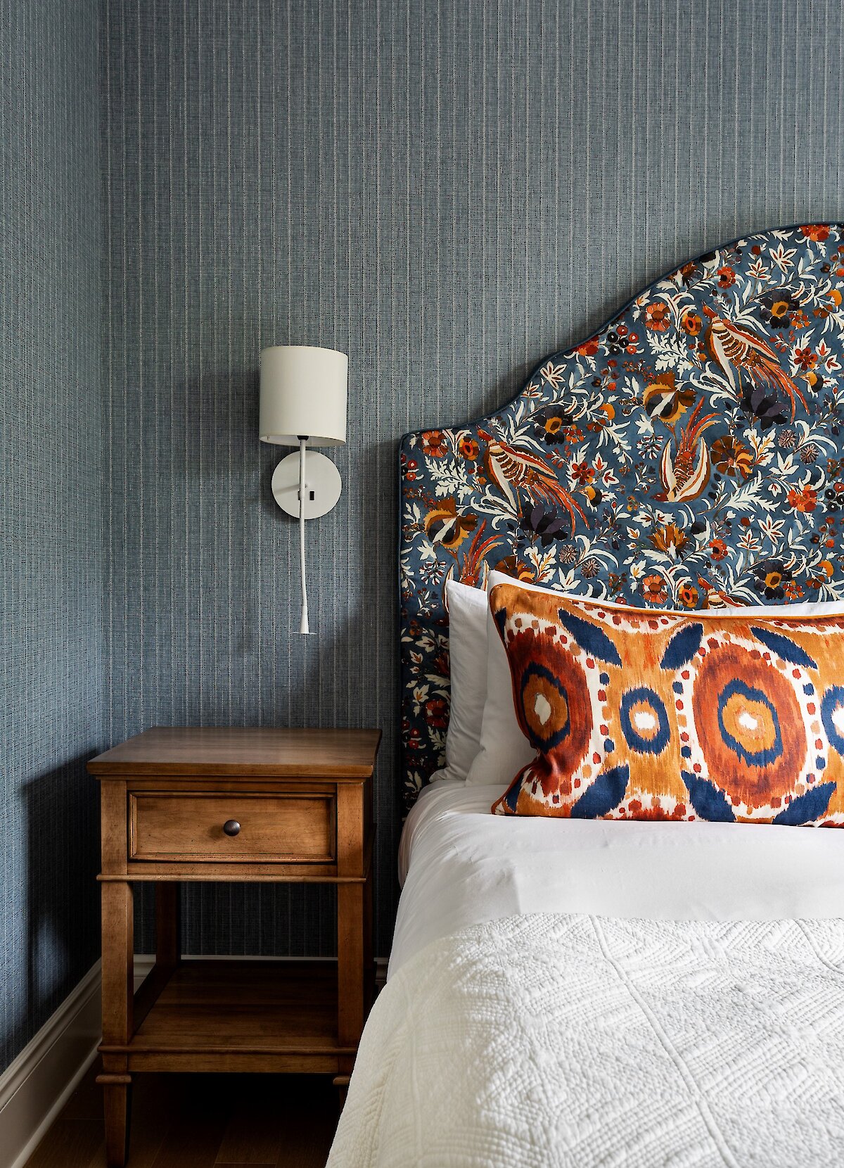 A bed with a bedside lamp and a nightstand