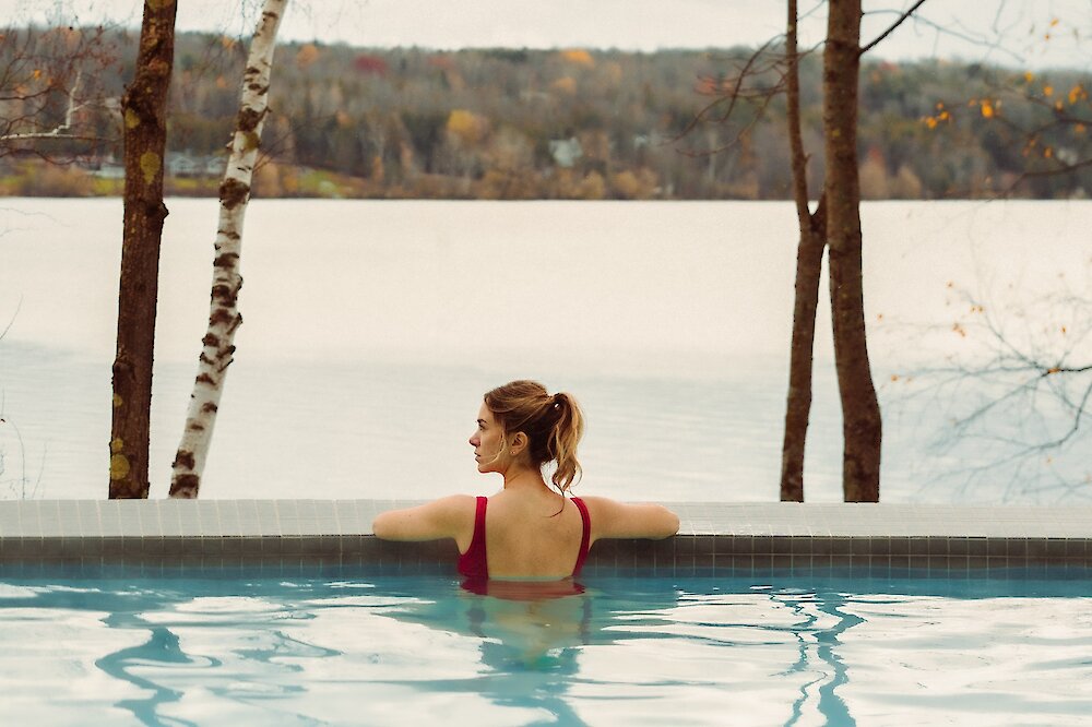 A woman is looking out at the view of the lake from the pool.