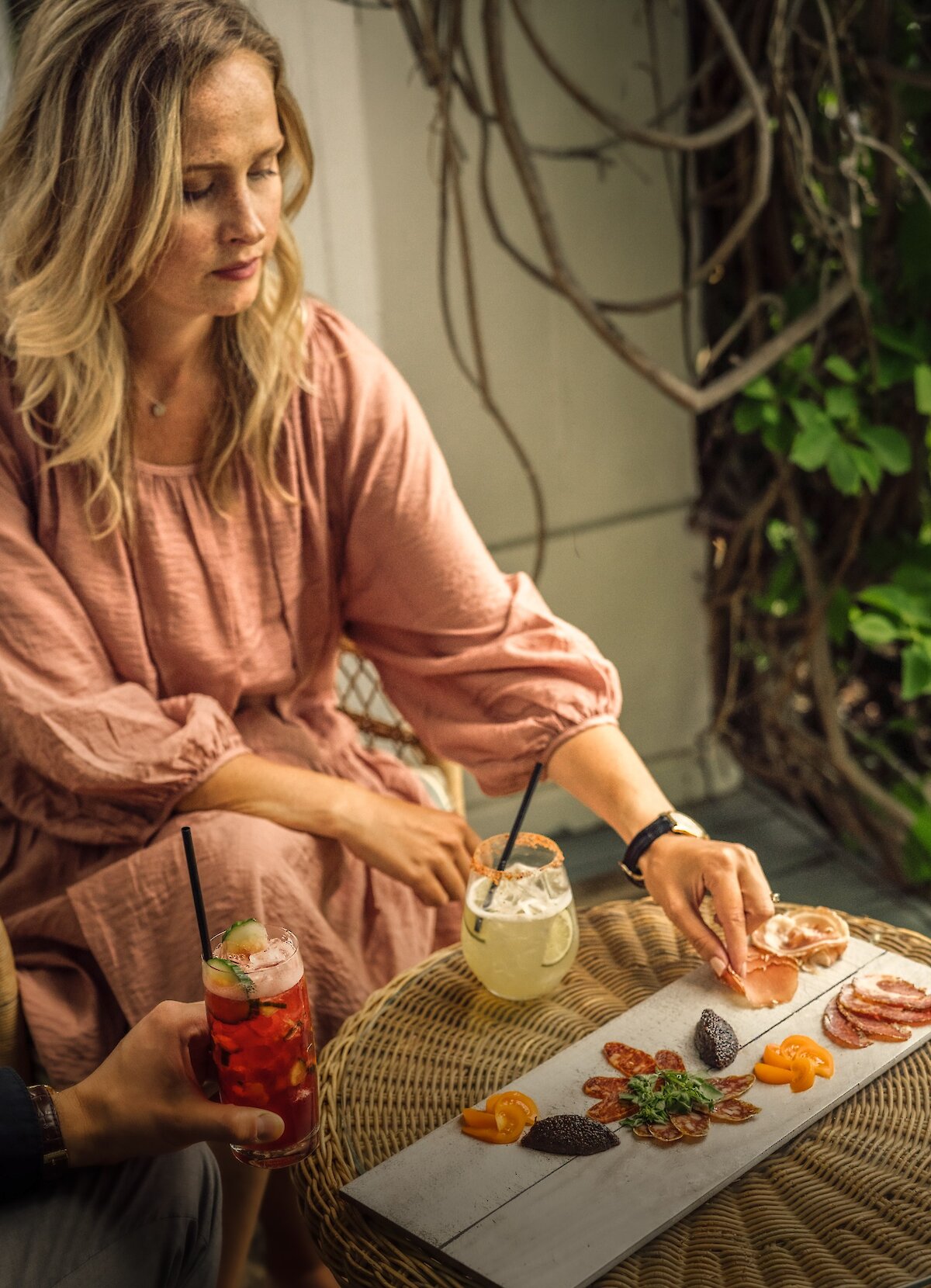 A woman in a dress is having a drink in the gardens.