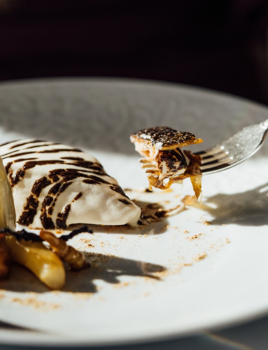 Un dessert raffiné dressé avec délicatesse, agrémenté d’une crème onctueuse et d’une sauce riche, dans une ambiance intime.