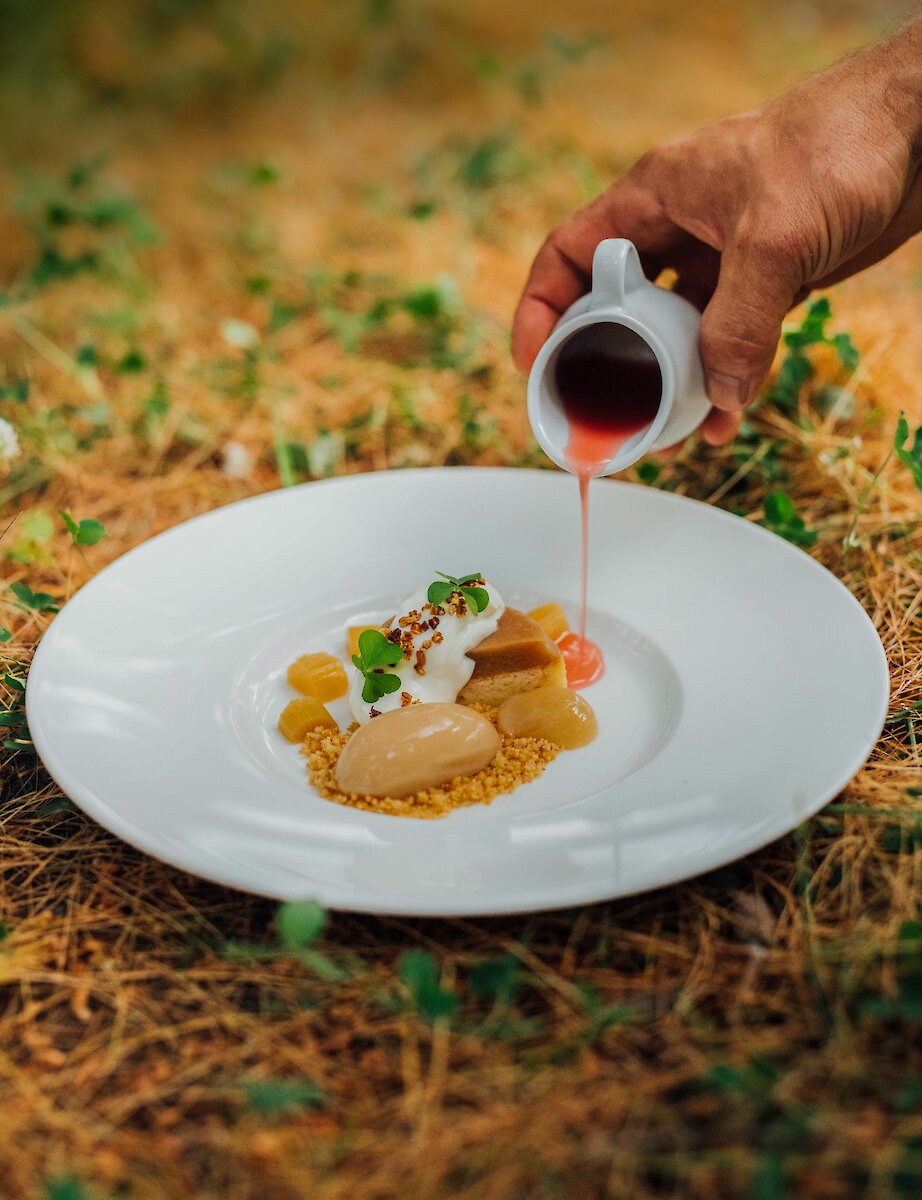 An elegant dessert plated in nature, finished with a sauce poured by hand.