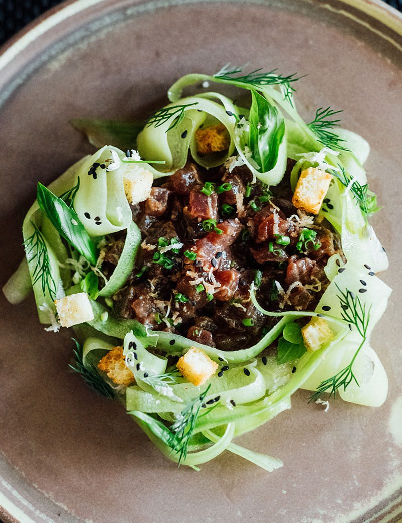 Une assiette avec du tartare de thon et des concombres