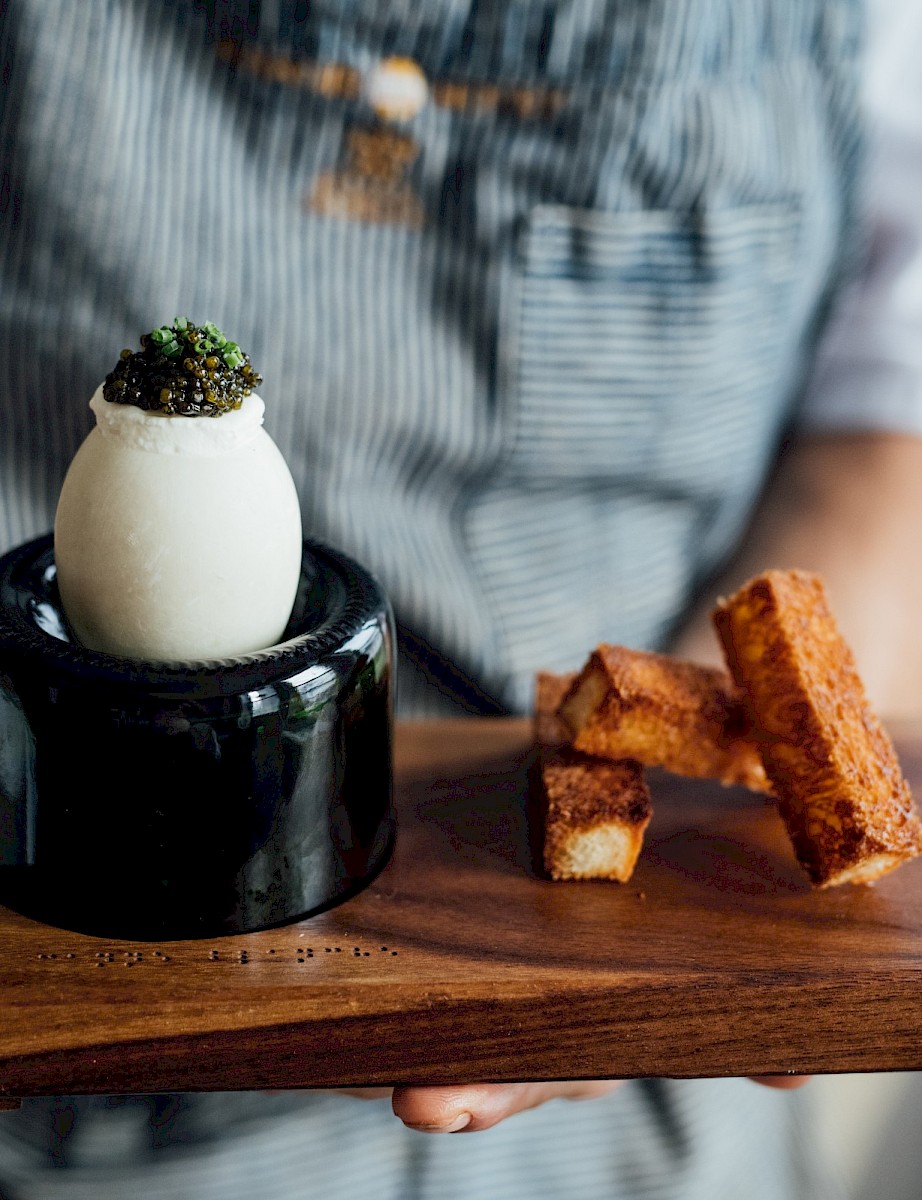 A duck egg with caviar on a wooden board