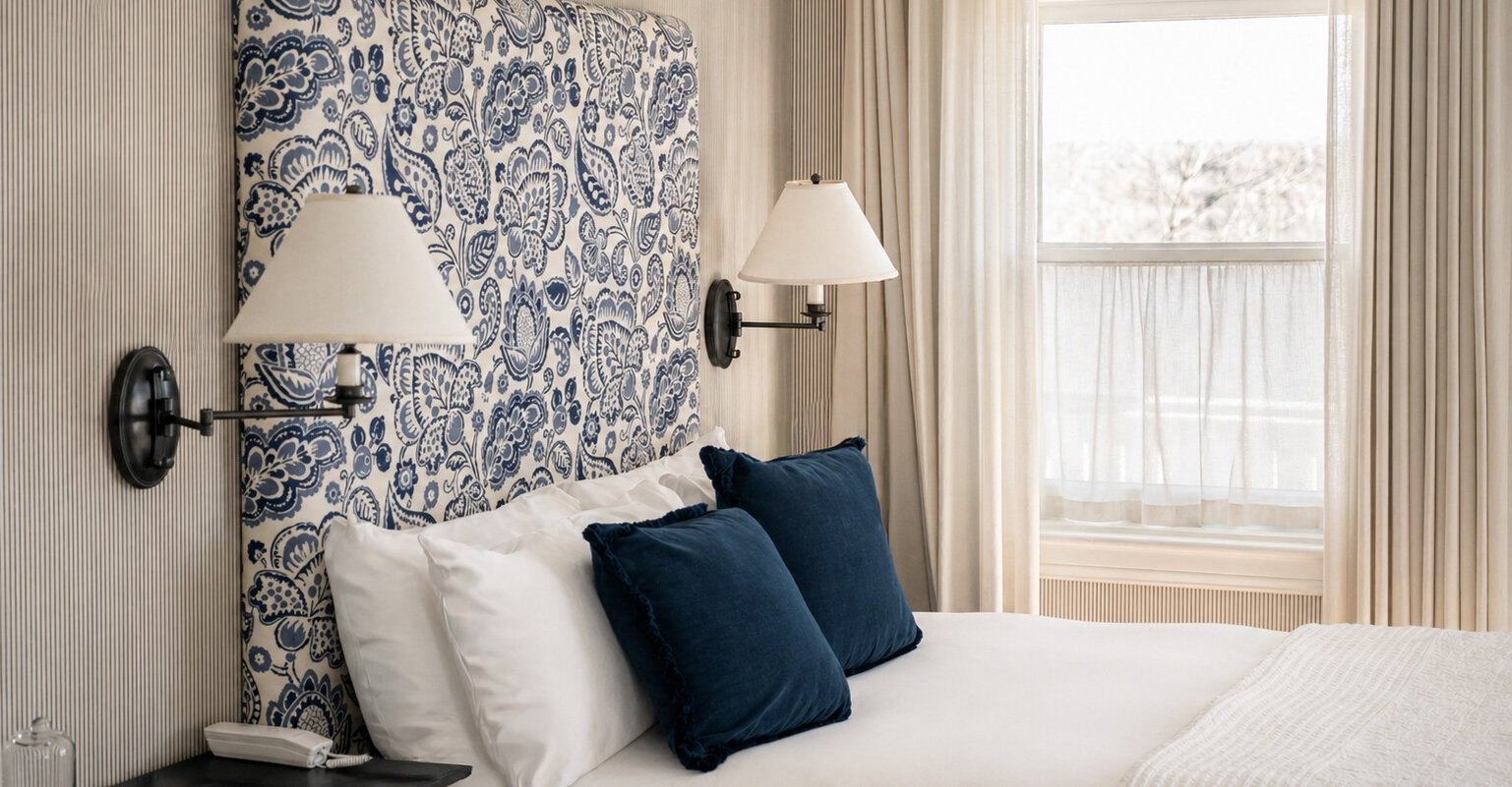 Chambre classique du Manoir Hovey avec tête de lit à motif bleu, literie élégante et lumière naturelle près de la fenêtre