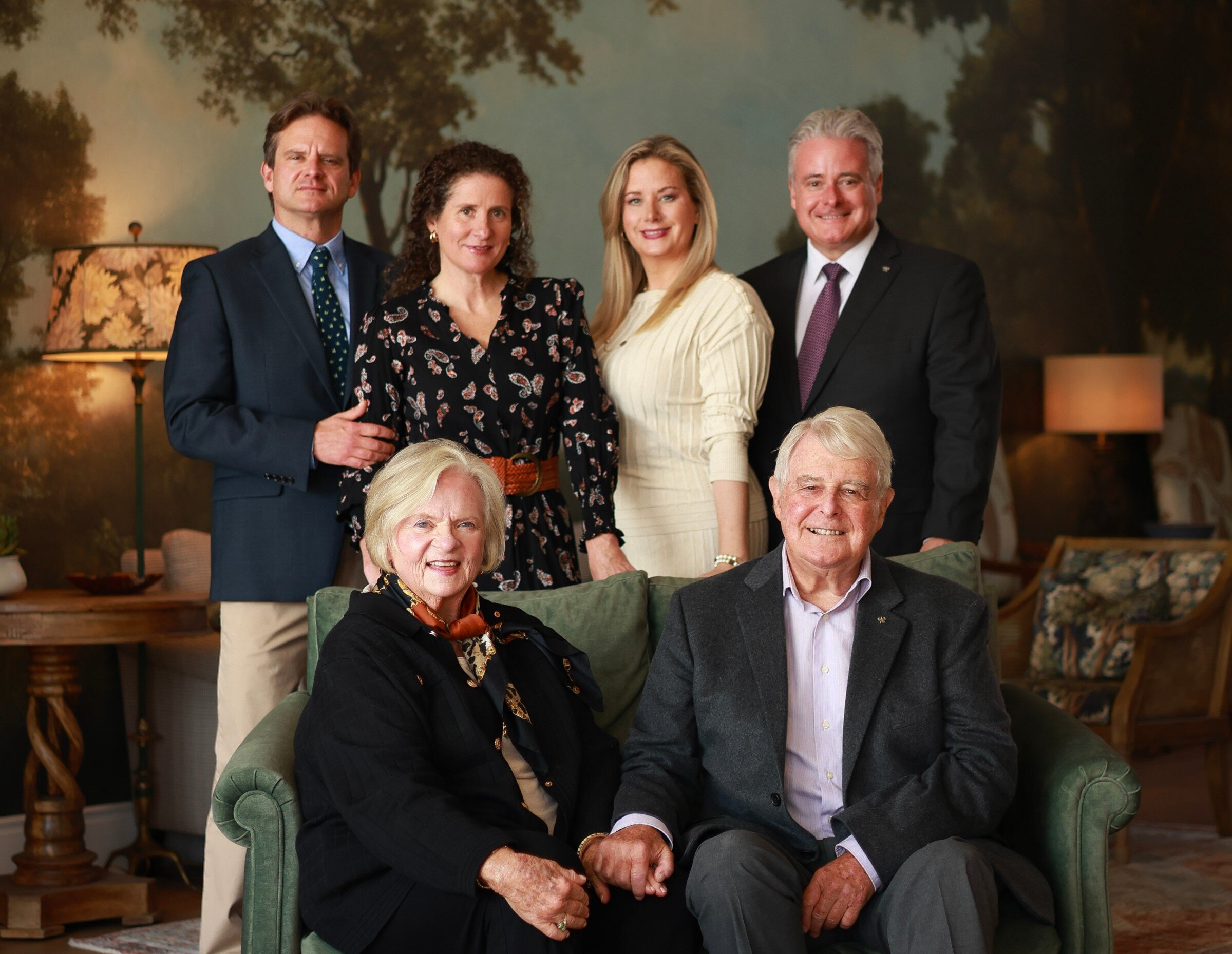 Portrait élégant d’une famille multigénérationnelle dans un intérieur chaleureux et raffiné.