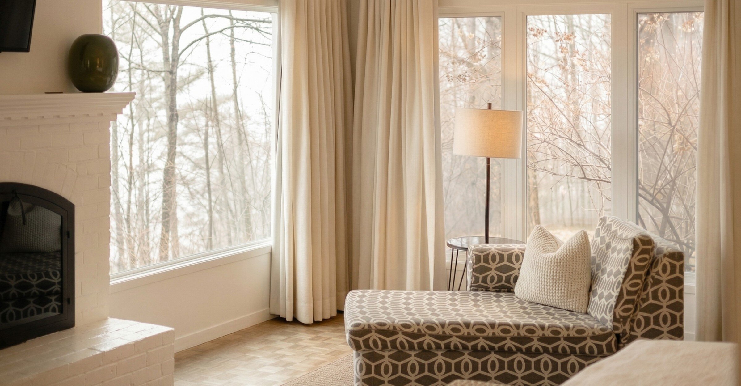Chambre lumineuse avec grandes fenêtres, coin détente avec méridienne, vue sur la nature.