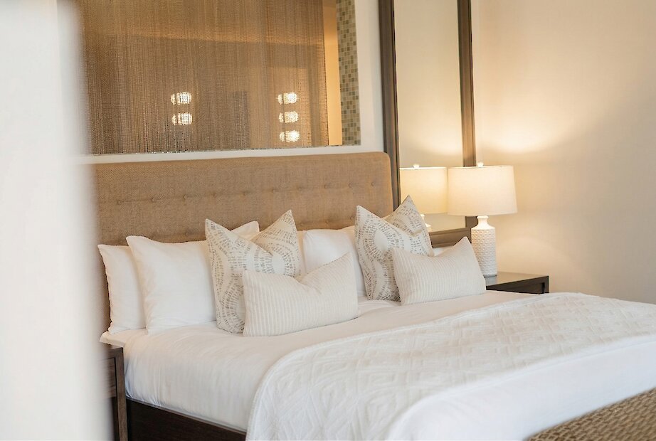 Chambre élégante avec lit king, tête de lit rembourrée, ambiance douce et lumineuse.