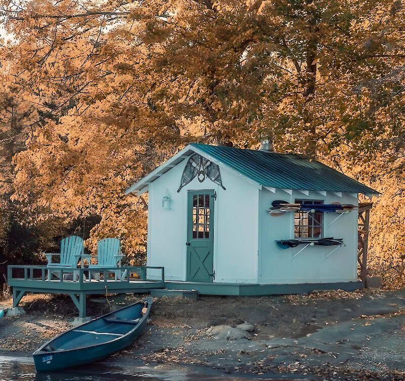 Une petite maison au bord du lac avec un canoë sur la plage