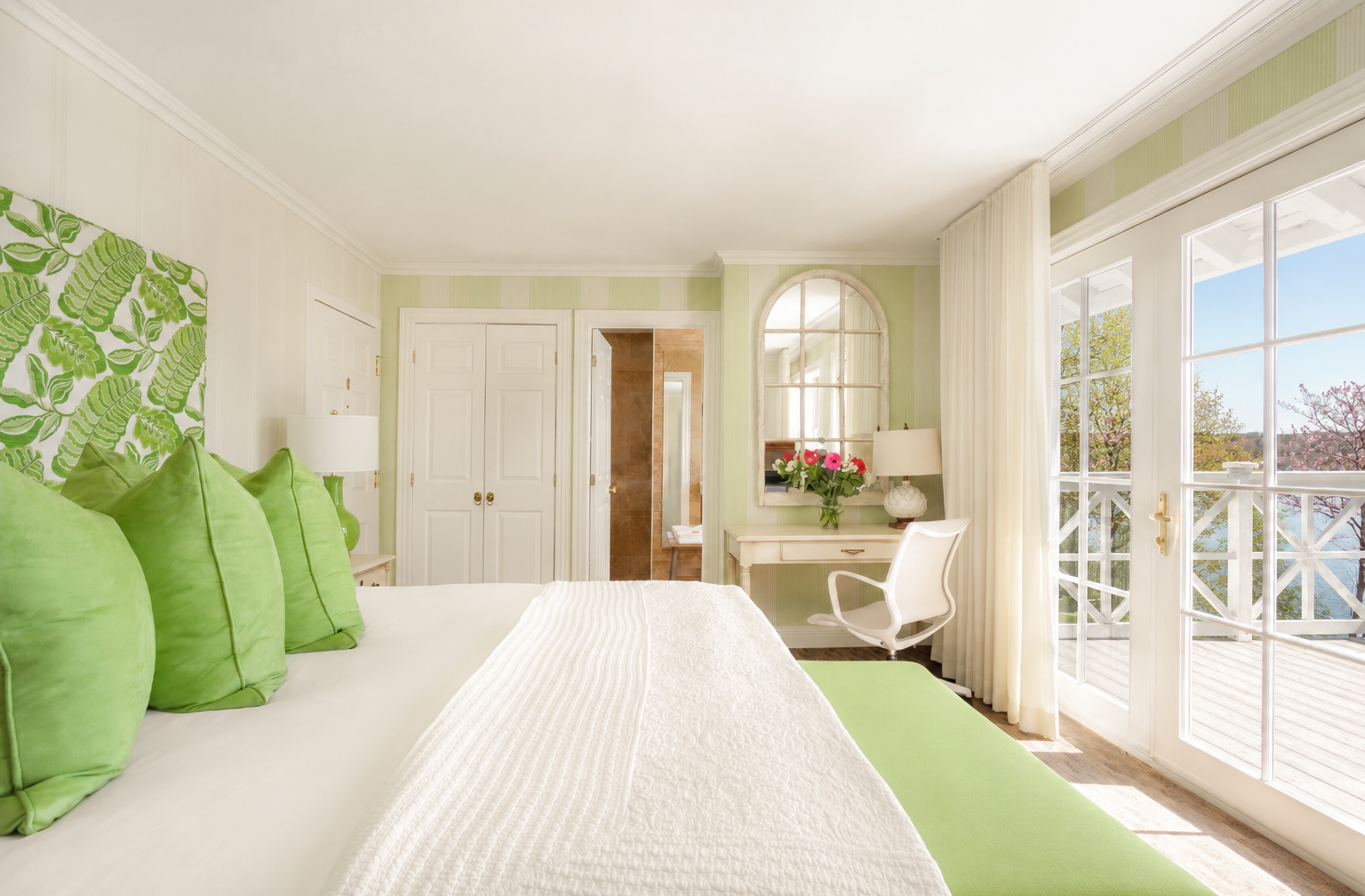 Chambre lumineuse aux accents verts avec vue depuis le balcon.