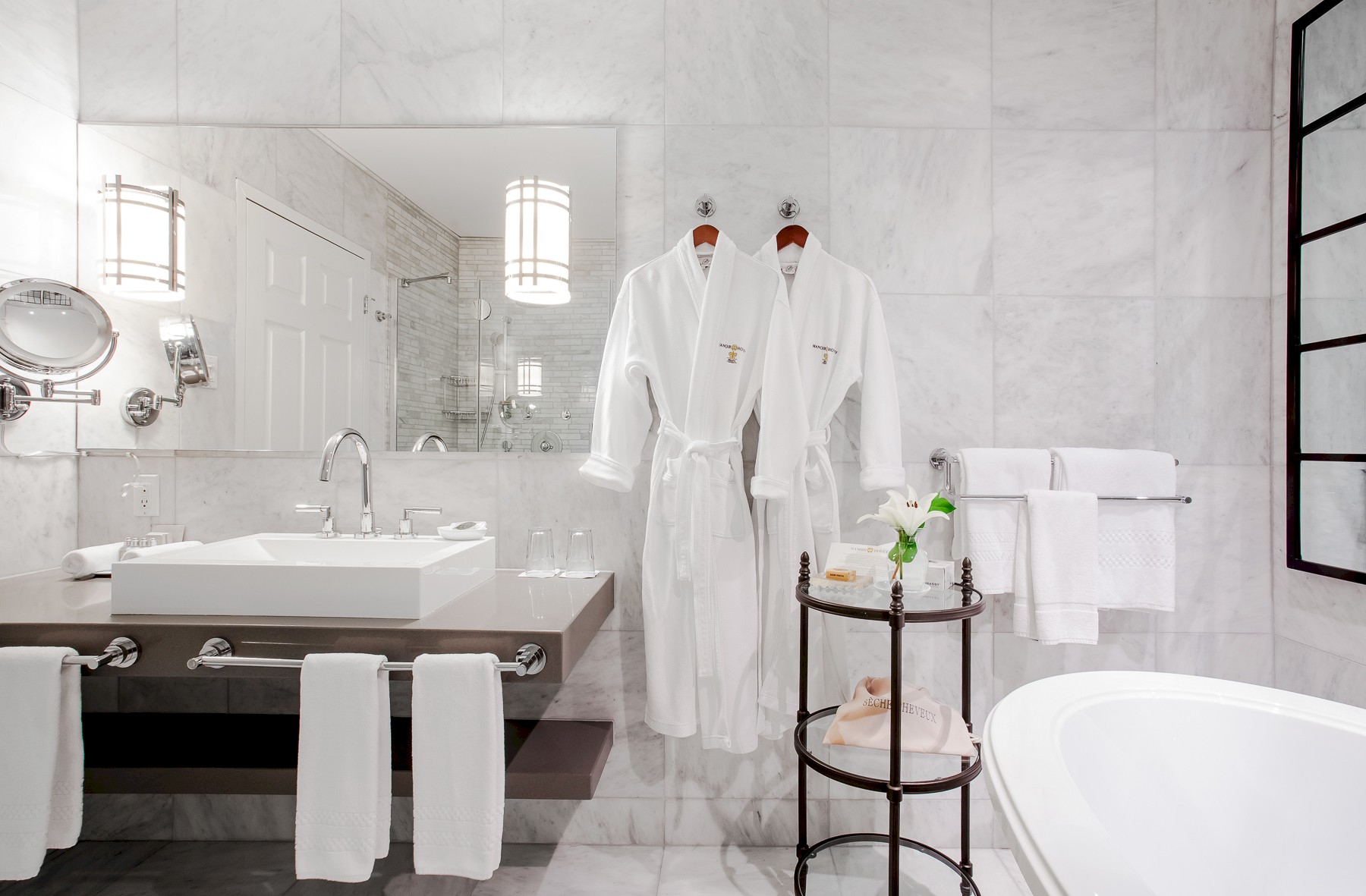 Salle de bain en marbre blanc avec des peignoirs
