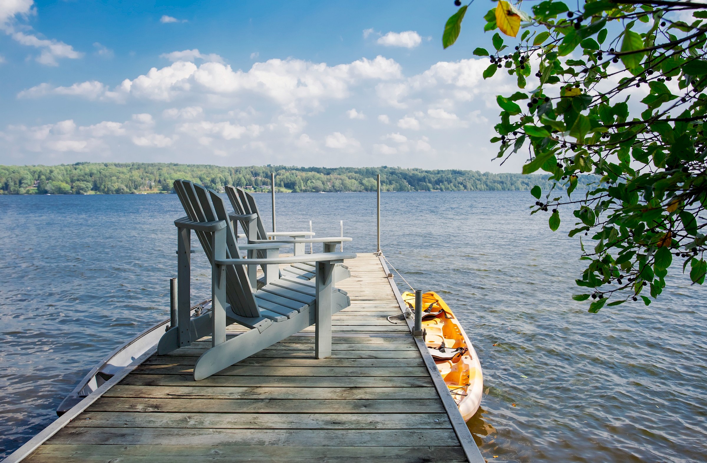 Wooden dock on the lake with two chairs and a kayak