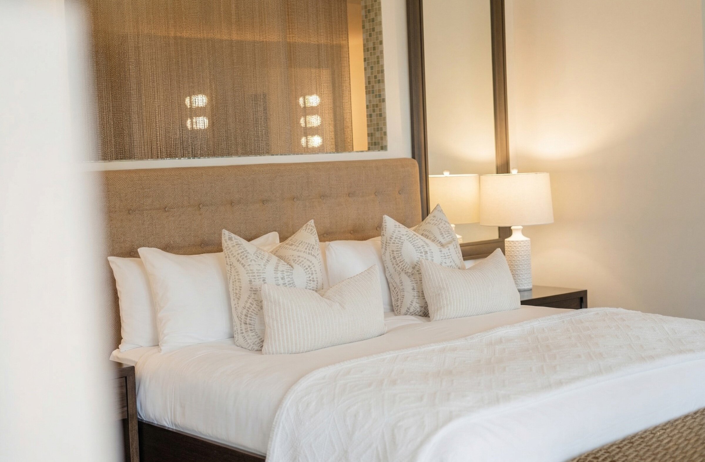 Chambre élégante avec lit king, tête de lit rembourrée, ambiance douce et lumineuse.