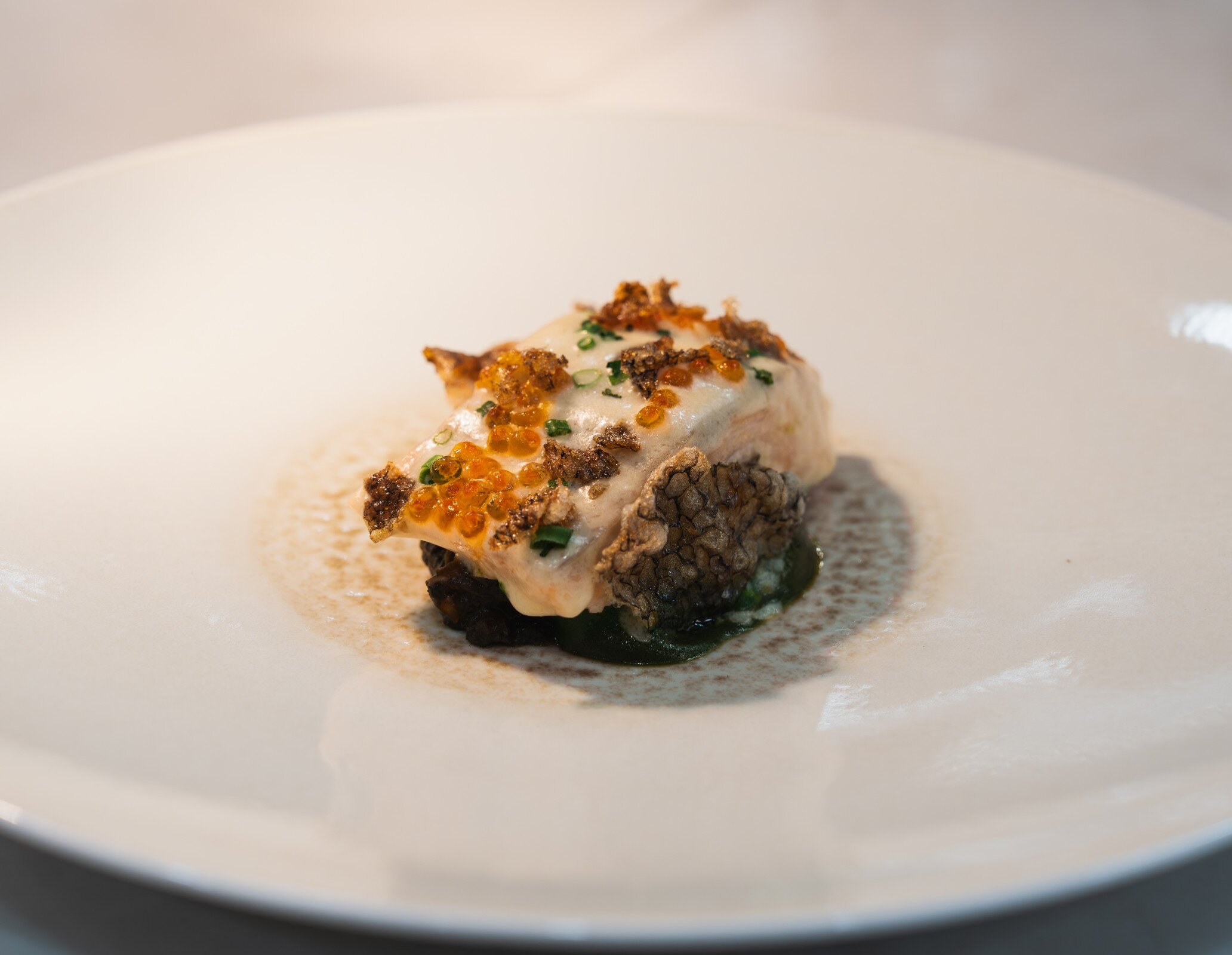 Delicately cooked fish with a light glaze, topped with trout roe, chives, and crispy accents. Served over a smooth green purée with a subtle, aromatic sauce.