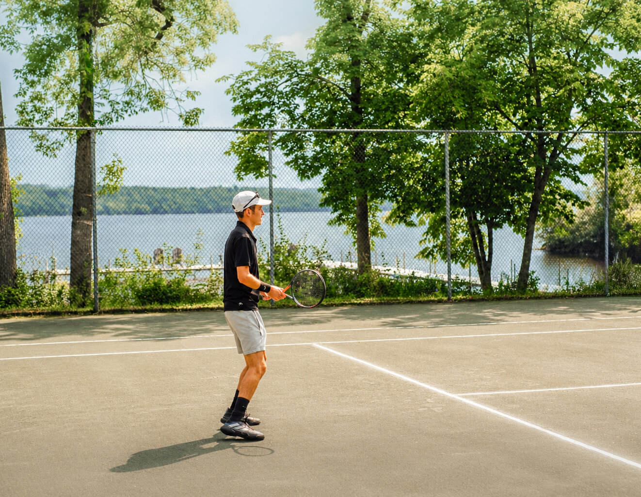 A man is playing tennis by the lake.