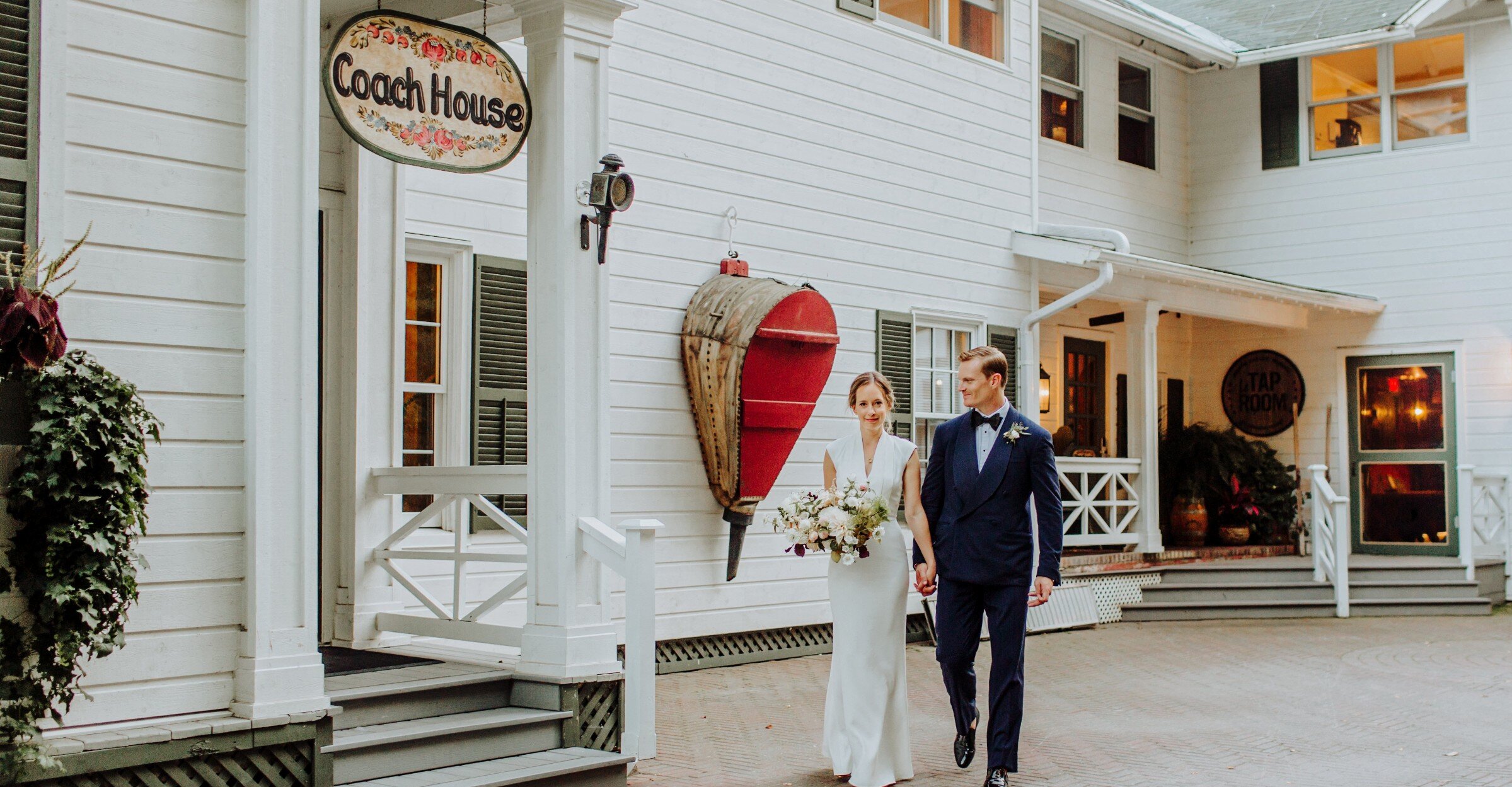 Groom and bride walking in front of the Coach House