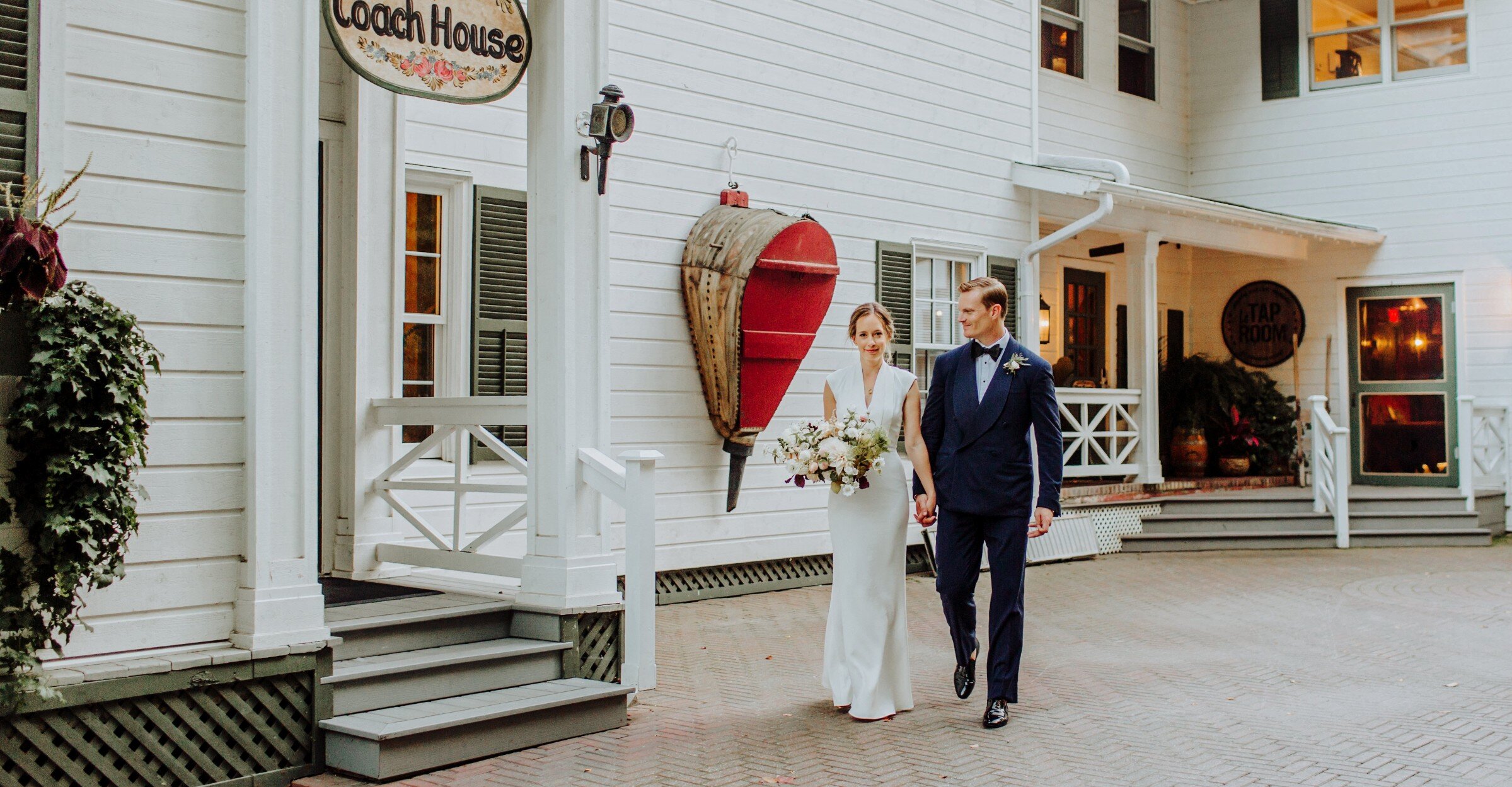 Groom and bride walking in front of the Coach House