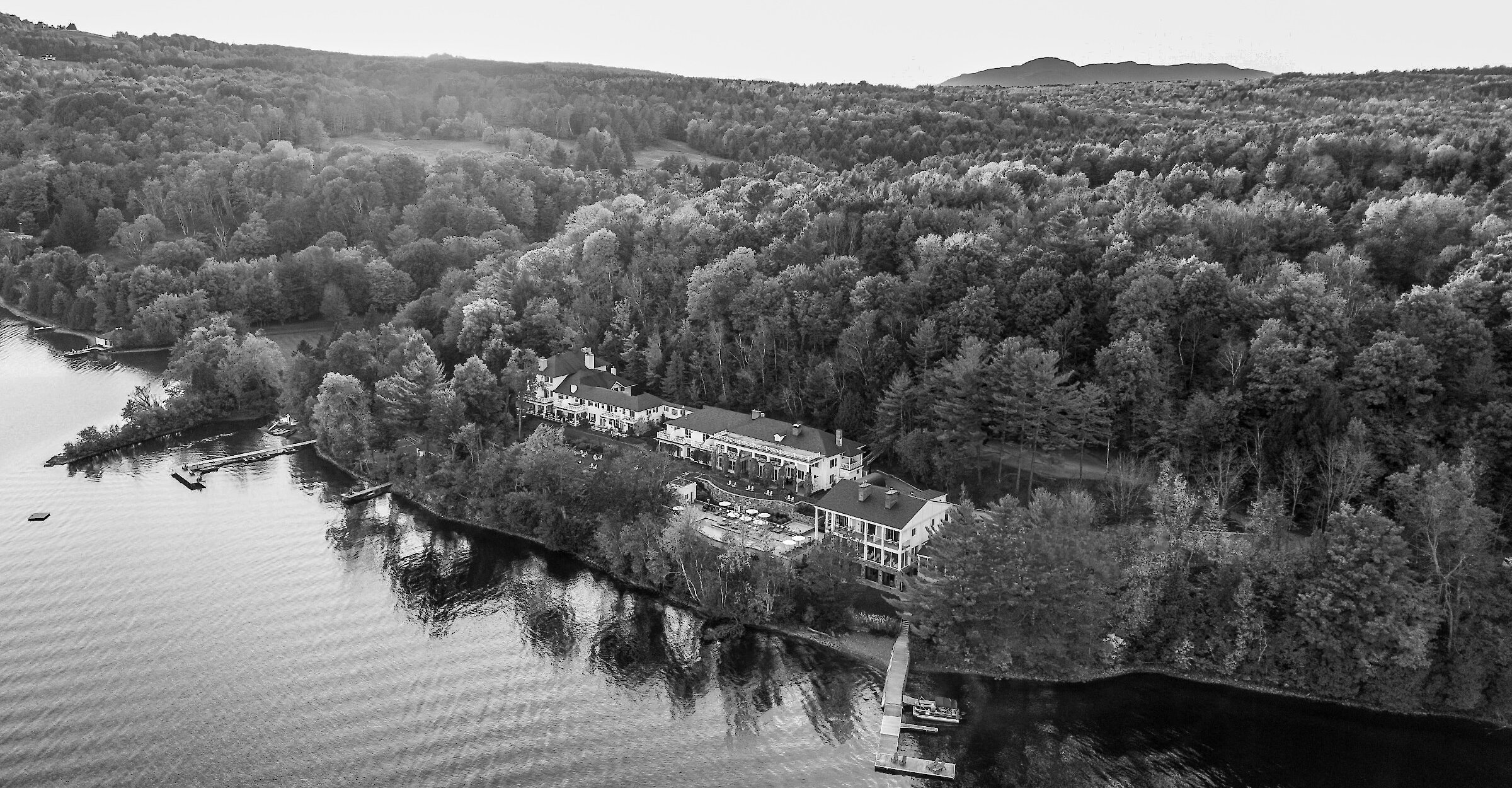Aerial view of Manoir Hovey on the shores of Lake Massawippi, surrounded by forest.