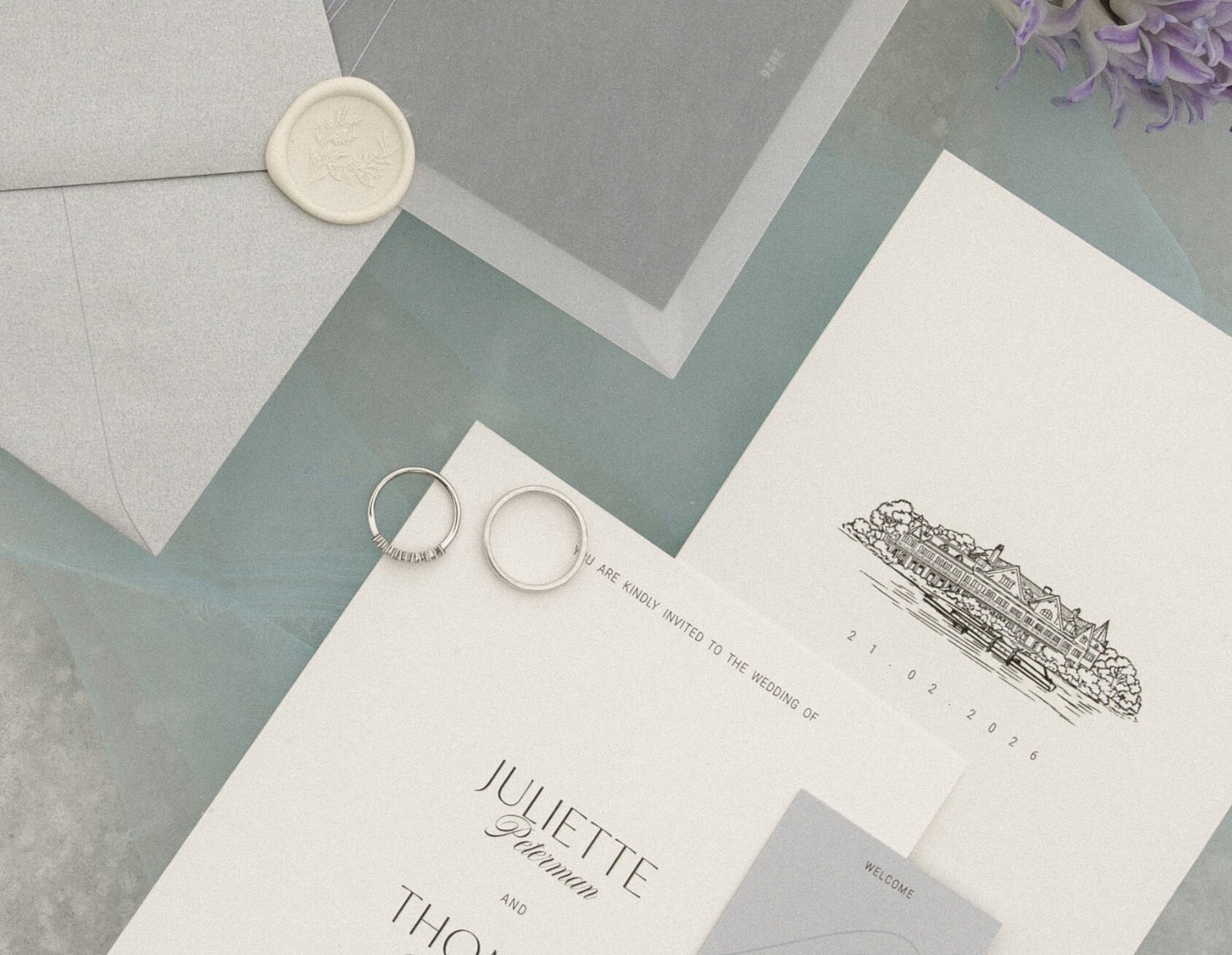 Papeterie de mariage élégante en vue à plat, avec alliances, textures douces et design minimaliste raffiné.