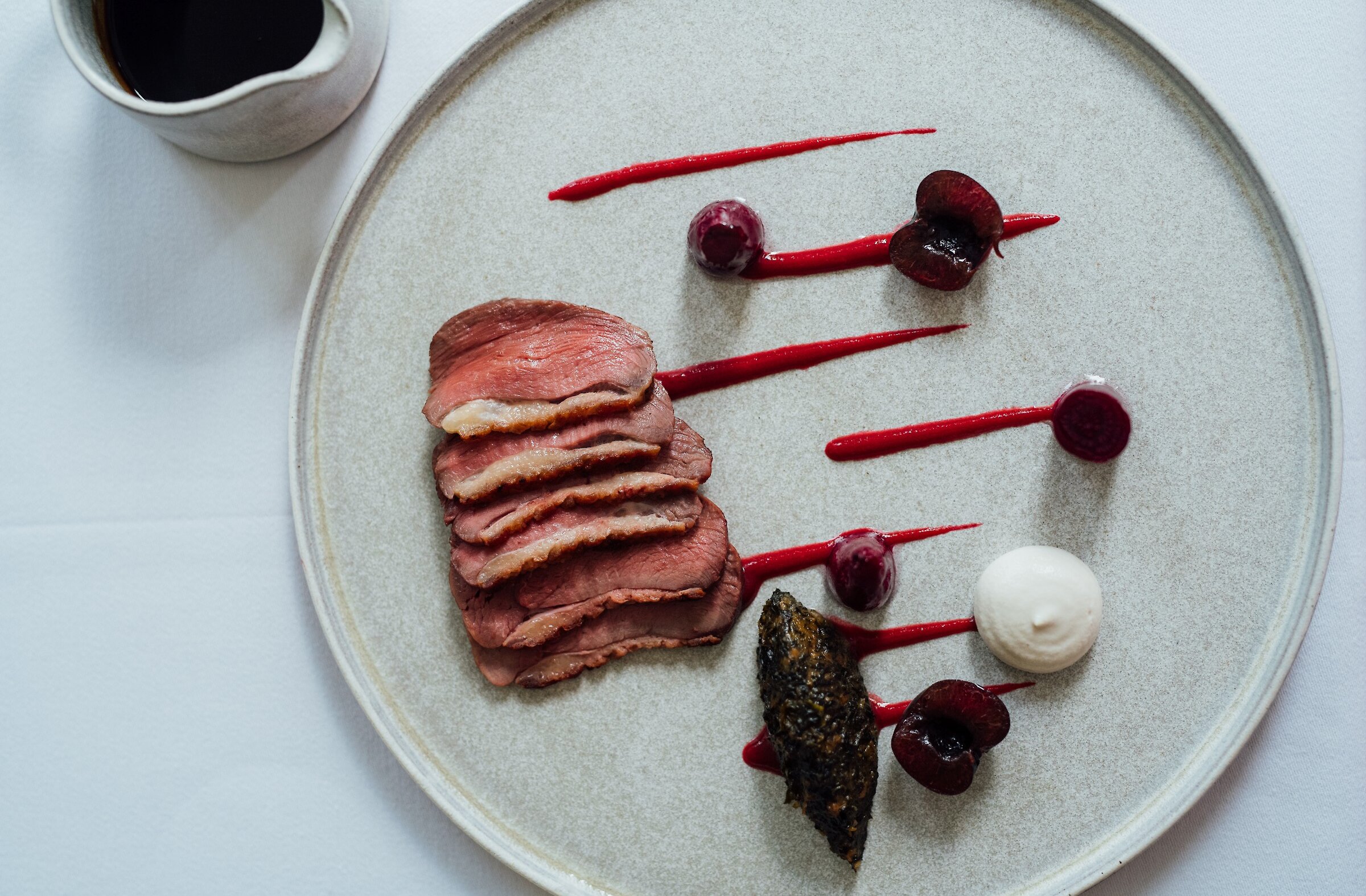 A plate of duck, beets and cherries