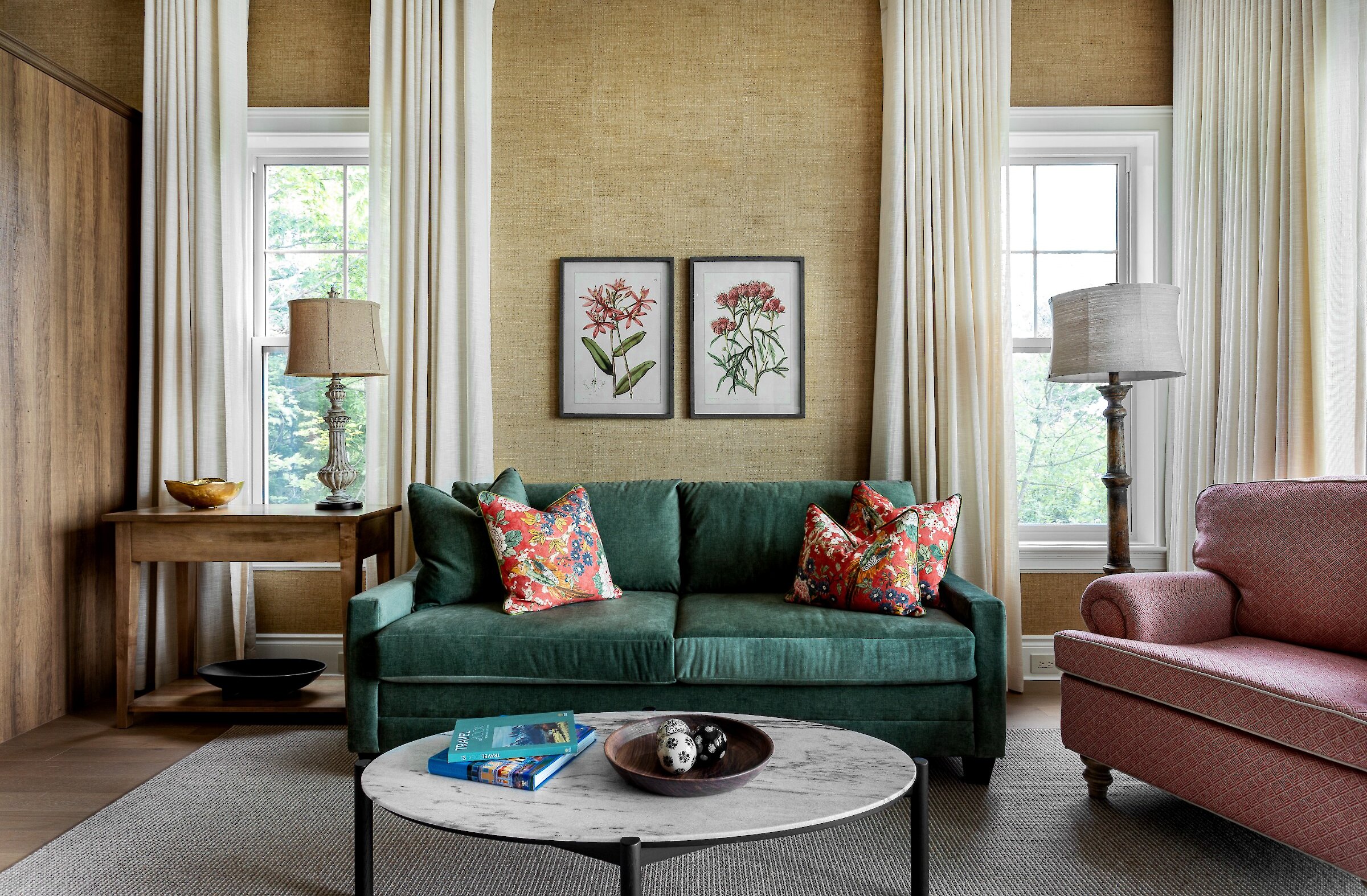 A green sofa surrounded by two lamps and frames on the wall