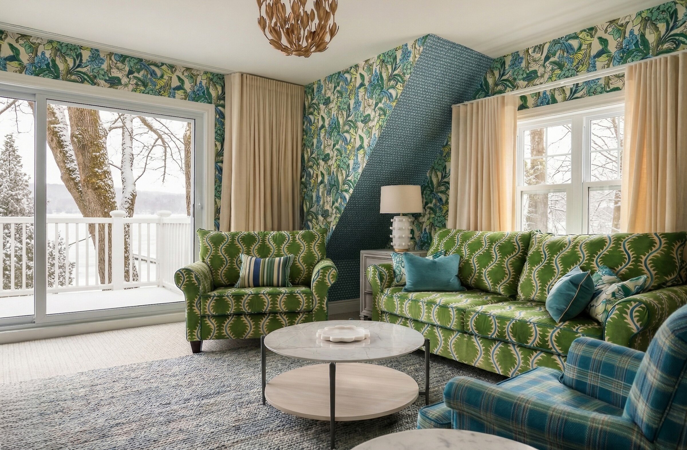 Espace salon lumineux avec coin détente, canapé et fauteuils, ouvert sur un balcon privé avec vue sur le lac Massawippi. Décor raffiné aux motifs inspirés de la nature et textures chaleureuses.