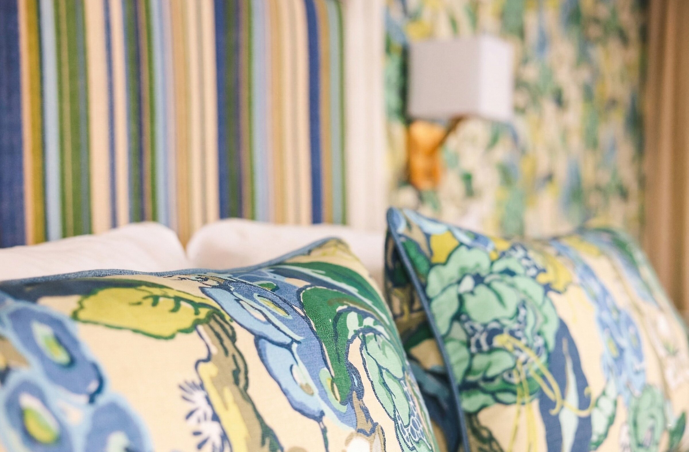 Détail du linge de lit et des coussins aux motifs botaniques, mettant en valeur les textures et la palette naturelle de la suite.