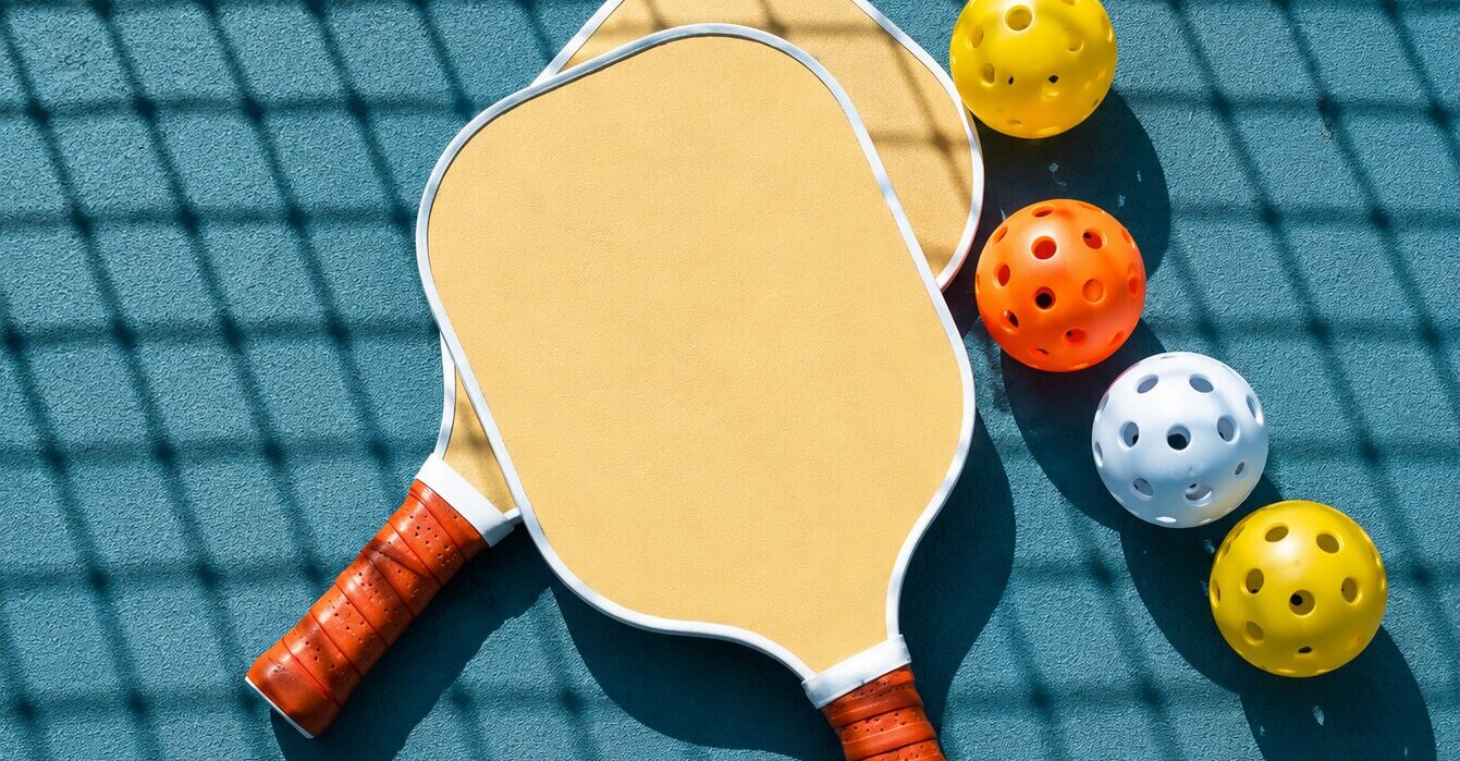 Raquettes et balles de pickleball sur un terrain extérieur, dans une ambiance sportive et élégante.