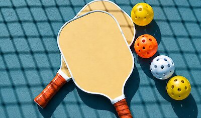 Pickleball paddles and balls on an outdoor court, creating a sleek and sporty atmosphere.