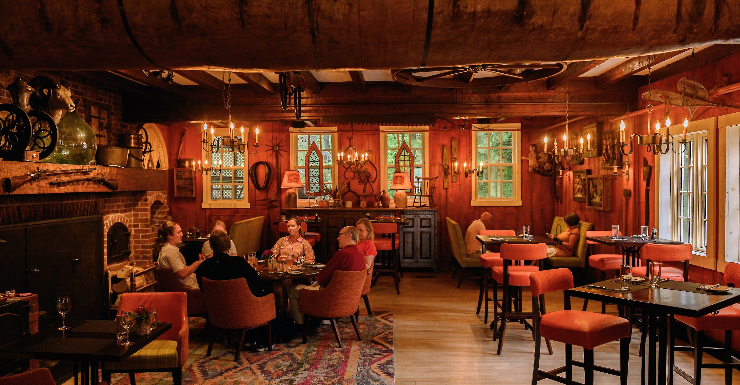 Une salle à manger rustique et chaleureuse, avec des poutres en bois, un éclairage tamisé et une cheminée, créant une atmosphère intime et accueillante.
