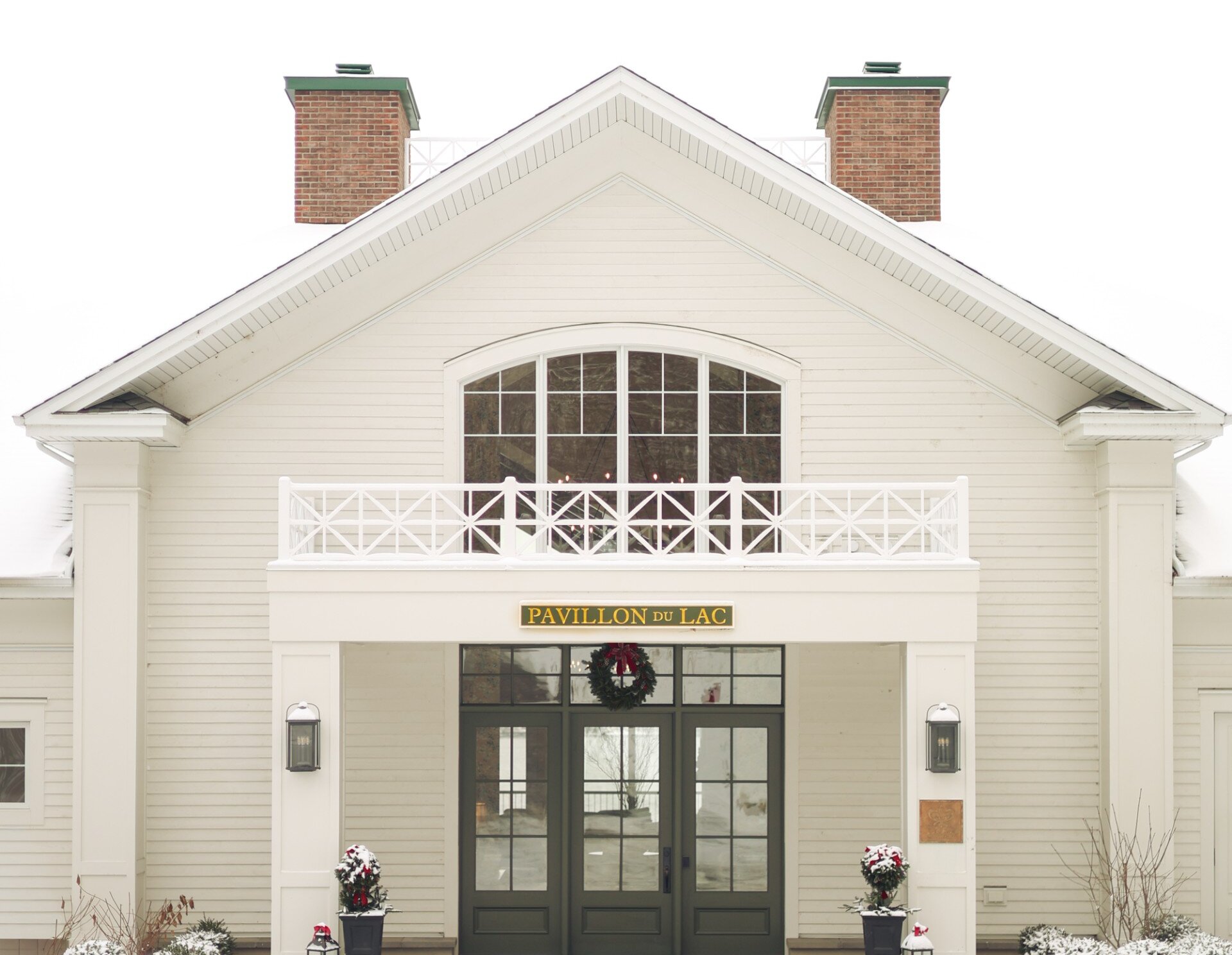 Extérieur d'un hôtel en hiver, avec une entrée enneigée et une architecture classique.