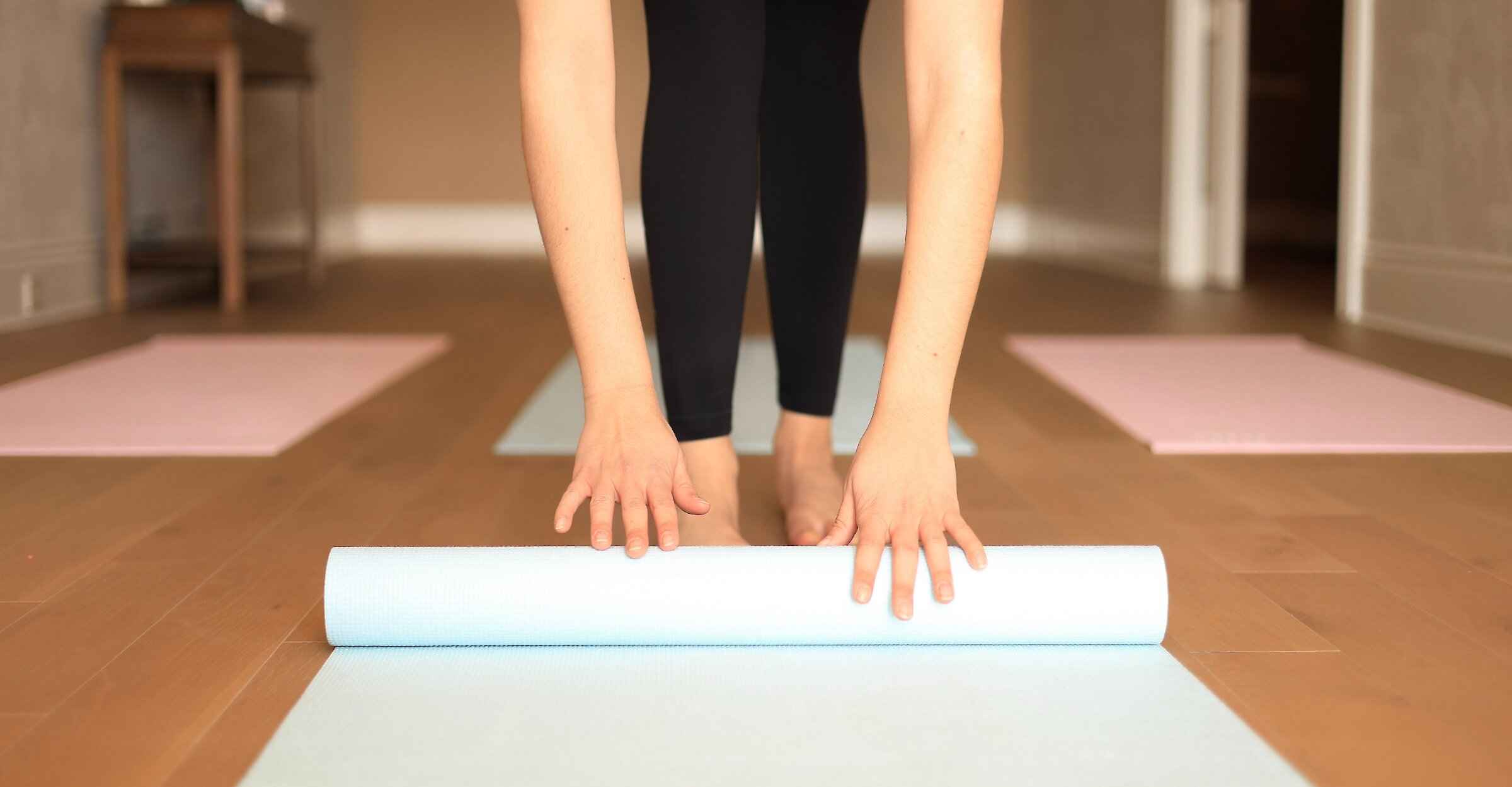 des mains déroulant un tapis de yoga pour se préparer à des étirements dynamiques